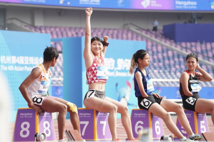 10月25日上午，杭州亚残运会女子100米T47级决赛在黄龙体育中心进行，中国代表团田径运动员李露以12秒63夺得金牌，赛场上，这个阳光开朗的独臂女孩露出她标志性的笑容，向全场观众挥手致意。图源：潮新闻