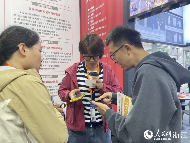 客商与双童商学院工作人员互加联系方式。人民网记者 王丽玮摄